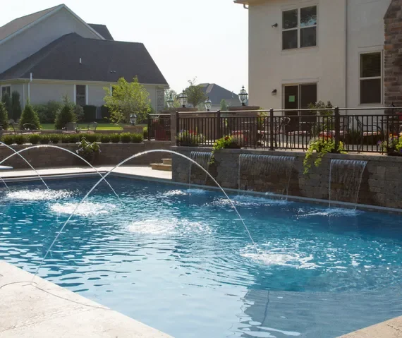 Custom backyard swimming pool with fountains and stone waterfall